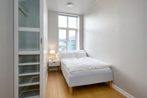 ein weißes Schlafzimmer mit einem Bett und einem Fenster in der Unterkunft Elegant Bergen City Center Apartment - Ideal for business or leisure travelers in Bergen