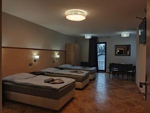 pokój z trzema łóżkami, stołem i krzesłami w obiekcie Hotel Cade w Piosku