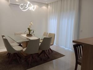 une salle à manger avec une table et des chaises en verre dans l'établissement Casa para Veraneio em Torres, à Torres