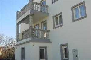 - un bâtiment blanc avec un balcon sur le côté dans l'établissement Simple 3-room apartment, à Kukuljanovo