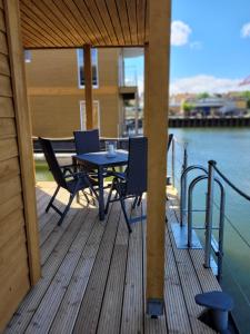 a wooden deck with a table and chairs on the water at 4 Sterne Dtv Floating House in Kröslin