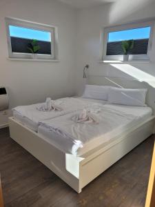 a white bed in a bedroom with two windows at 4 Sterne Dtv Floating House in Kröslin