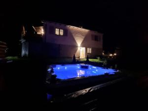 ein Haus mit blauem Pool vor einem Haus in der Nacht in der Unterkunft Schöne Ferienwohnung mit Jacuzzi in Hinterzarten in Hinterzarten