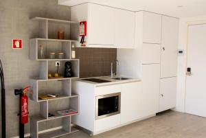 a kitchen with white cabinets and a red fire hydrant at Casa das Falcoeiras - Estúdio com terraço privado in Aveiro
