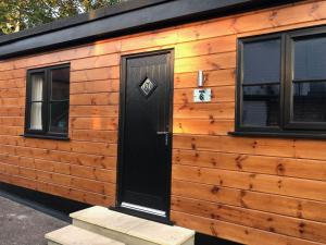 a log cabin with a black door and two windows at The Castle in Norwich