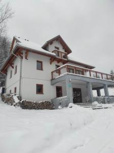 una casa blanca con nieve en el suelo en Gościniec Śliwkula en Jaworzynka
