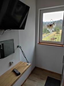 a room with a television and a desk with a window at Gościniec Śliwkula in Jaworzynka