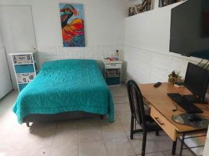 a bedroom with a bed and a desk with a computer at LA CASA DE CLAU in Sarandí