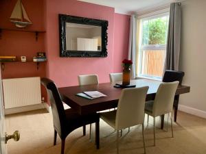 een eetkamer met een tafel en stoelen en een spiegel bij Smart & Comfortable 3-bedroom Victorian house in Stalham