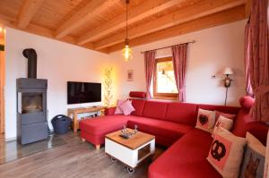 a living room with a red couch and a fireplace at Feriendorf Via Claudia Haus 81 Eulennest in Lechbruck