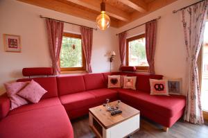 um sofá vermelho numa sala de estar com janelas em Feriendorf Via Claudia Haus 81 Eulennest em Lechbruck
