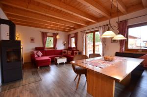 a living room with a table and a red couch at Feriendorf Via Claudia Haus 81 Eulennest in Lechbruck