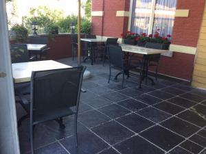 een terras met tafels en stoelen in een restaurant bij L'auberge in Baronville
