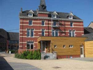 un grand bâtiment en briques rouges avec un toit dans l'établissement L'auberge, à Baronville