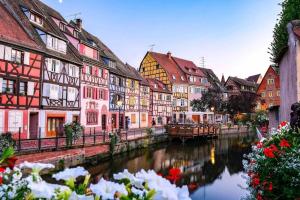 um grupo de edifícios coloridos ao lado de um rio em Le trésor de Khalis em Colmar