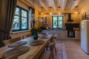 a kitchen with a wooden table with chairs and a refrigerator at Willa Zielona Jabłonka in Nidzica