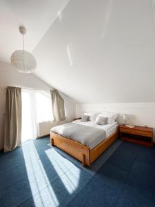 a white bedroom with a bed and a large window at Fado Apartments Lendava in Lendava