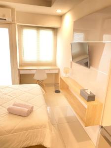 - une chambre avec un lit, un bureau et une télévision dans l'établissement Apartemen Grand Sentraland by My room, à Karawang