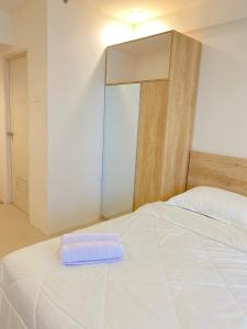 - un lit blanc avec une serviette bleue dans l'établissement Apartemen Grand Sentraland by My room, à Karawang