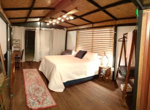 1 dormitorio con cama blanca y suelo de madera en Zil-Kaab Hidden Glamping Village, en Tulum