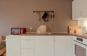 a kitchen with white cabinets and a sink and a microwave at Unique Boathouse - Central - Kajak - Fitness in Strendur