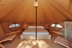 a bed in a tent with two windows at Camping Resort-Bungalow Park Mas Patoxas in Pals
