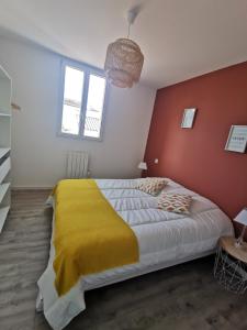 a bedroom with a large bed with a yellow blanket at Charmante maison au coeur du village de Saint-Trojan-les-Bains in Saint-Trojan-les-Bains