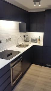 a kitchen with black cabinets and a sink at The Picture House Stylish Apartment in Fowey in Fowey