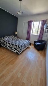 a bedroom with a bed and a chair on a wooden floor at Departamento en increíble ubicación in Mendoza