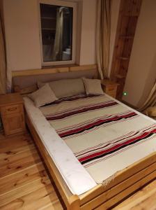 duże łóżko w pokoju z drewnianą podłogą w obiekcie Gościniec Śliwkula w mieście Jaworzynka