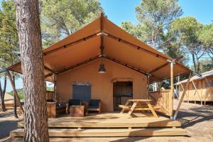 ein Zelt mit einem Tisch und einem Baum in der Unterkunft Camping Resort-Bungalow Park Mas Patoxas in Pals