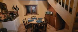 una cocina con una mesa con sillas y una escalera en La Boriette du Rougier, en Montlaur