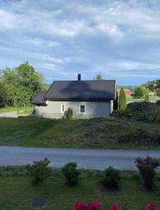 a white house with a black roof on a hill at Familievennlig leiligheten leies ut på Sørlandet. in Vennesla