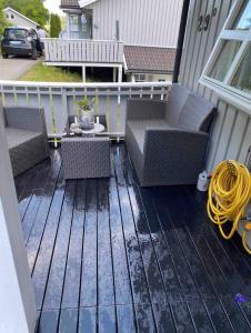 a deck with two wicker chairs and a table at Familievennlig leiligheten leies ut på Sørlandet. in Vennesla