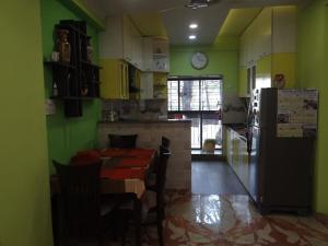 a kitchen with green walls and a table and a refrigerator at Stylish, Luxurious Home Getaway in Kolkata