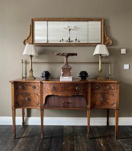 a wooden dresser with two lamps and a mirror at Luxurious Converted Old Victorian Bank Building in Stewartstown