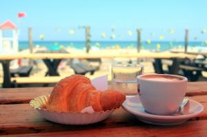 a pastry and a cup of coffee on a table near the beach at Camping Serenella in Rodi Garganico