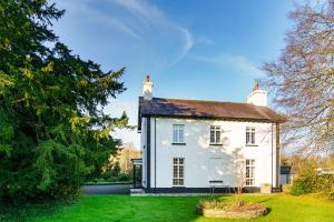 a white house in a yard with a tree at Ty Bledrws - family retreat near the Cardigan Bay coast in Llangybi