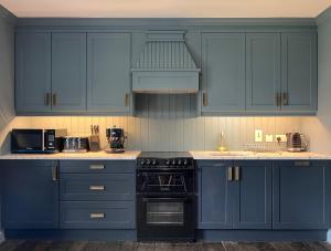 a kitchen with blue cabinets and a stove top oven at Luxurious Converted Old Victorian Bank Building in Stewartstown