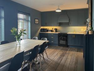 uma cozinha com armários azuis e uma mesa e cadeiras de madeira em Luxurious Converted Old Victorian Bank Building em Stewartstown