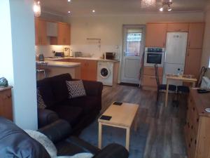 uma sala de estar com um sofá e uma cozinha em The Annex - Guest Gardens em Milton Keynes