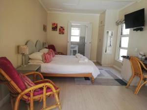 a bedroom with a bed and two chairs and a television at Maroela House Guest Accommodation in Bellville