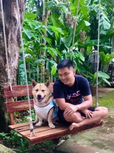 a man and a dog sitting on a swing at Eden House & Coffee Con Dao in Con Dao