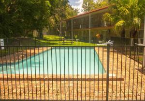 a swimming pool behind a fence in front of a building at Coomera Motor Inn in Gold Coast