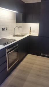 a kitchen with black cabinets and a sink at The Picture House Stylish Apartment in Fowey in Fowey