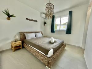 1 dormitorio con cama de mimbre y ventana en Villa en bord de mer, vue mer au Diamant, en Le Diamant