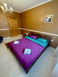 Una gran cama púrpura con 2 toallas encima. en Ruski Boulevard, en Plovdiv