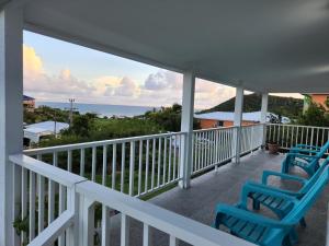 Un balcón con sillas azules y vistas al océano. en Red Snapper Guest House en Providencia