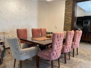 a dining room with a table and pink chairs at Royal Mariout Villa in King Mariout