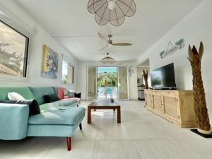 a living room with a blue couch and a tv at Villa en bord de mer, vue mer au Diamant in Le Diamant